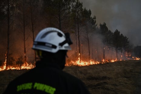 A firefighter walks in front of burning trees as a wildfire rages near Marcheprime, outside, Bordeaux, France