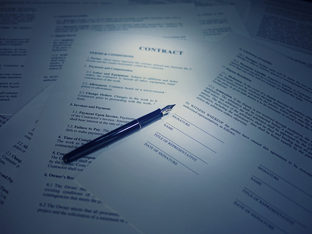 A pen resting on a printed contract document with signature lines