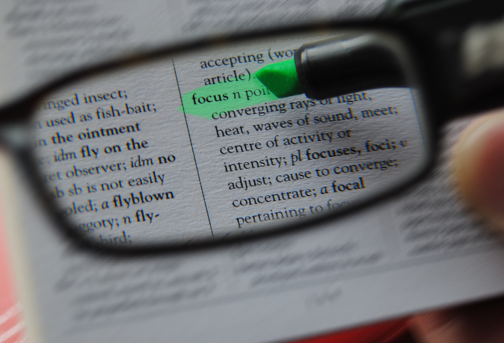 Close-up of a reader magnifying a printed document line by line with a magnifying glass, reviewing the fine print of a statement