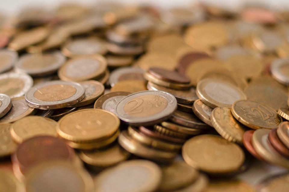 A pile of mixed international coins, including US cents and euro coins, illustrating currency conversion and exchange rates.